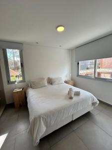 a white bedroom with a large bed and two windows at Edificio Cerezo 77 by D&G in Carilo +16 photos