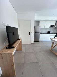 a living room with a tv and a kitchen at Edificio Cerezo 77 by D&G in Carilo