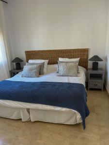 a bedroom with a large bed with blue blanket and pillows at Piso Frente al Mar - Marina de Alcaidesa in San Roque