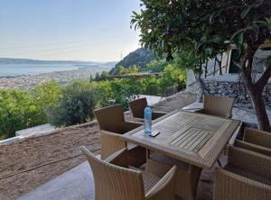 a wooden table with chairs and a bottle of water on it at Stone House Bay View - Kaštel Lukšić in Kaštela