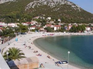 a beach with people laying on the sand and the water at Apartments Krvavac in Klek