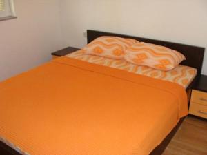 a bed with an orange blanket on top of it at Apartments Krvavac in Klek