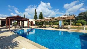 a swimming pool with chairs and umbrellas at Villa UNIDERA in Kouklia