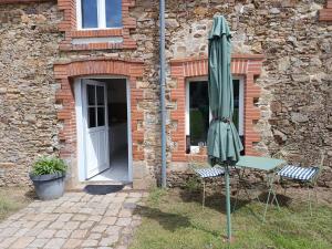 a green umbrella and two chairs and a building at Studio équipé, proche aéroport in Bouguenais