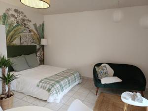 a bedroom with a bed and a chair at Studio équipé, proche aéroport in Bouguenais