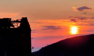un tramonto con il sole che tramonta dietro un edificio di Agriturismo Orto dei Rolli a Moneglia