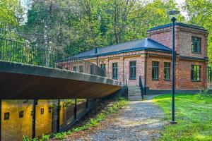 a brick building with a bridge in front of it at Via Baltica Panevezys Self Check-in Hotel in Panevėžys