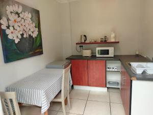 Una pequeña cocina con una mesa y un microondas. en Faerie Glen B&B, en Pretoria