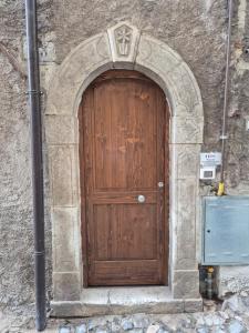 a wooden door in a stone building with a pole at Vico al 23, in pieno centro storico in Tagliacozzo