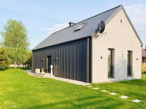 ein schwarz-weißes Gebäude mit einem Rasenhof in der Unterkunft LasMinute - stodoła z prywatną balią in Kazimierzów