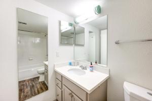 a white bathroom with a sink and a mirror at Cozy 2BR 2BA Condo in Houston Medical Center Free Parking & Fast Wi-Fi in Houston