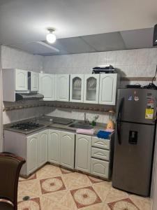a kitchen with white cabinets and a refrigerator at Gato Neon Hostel in Bogotá