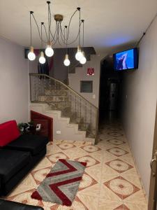 a living room with a black couch and a staircase at Gato Neon Hostel in Bogotá