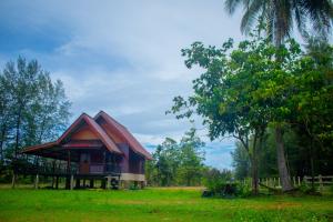 a small house with a red roof in a field at Sunee Seafood Bungalow in Ban Pak Klang