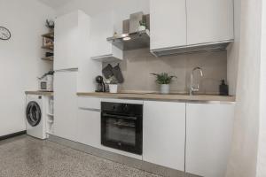 a kitchen with white cabinets and a sink and a dishwasher at Un nido a Boccadasse in Genova