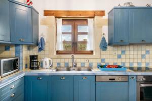 a blue kitchen with a sink and a window at Arodamos Villa with a pool, children's games, and BBQ, perfect for 23 people! in Skouloúfia