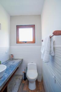 a bathroom with a white toilet and a sink at SantiChanti Walk to Sunzal Beach in Tamanique