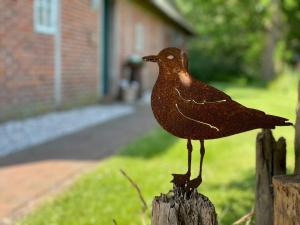 NorderfriedrichskoogReetdachhaus Für Erholsamen Familienurlaub的一只金属鸟栖息在木栅栏顶上