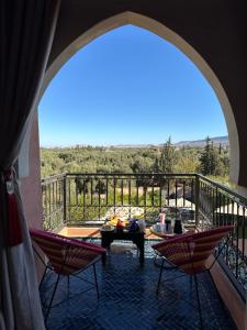 a room with a balcony with a table and chairs at Riad Timskrine in Ourika