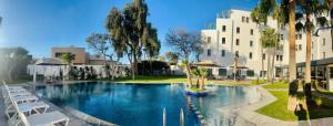 a large swimming pool with white chairs next to a building at Hotel Anna Agadir in Agadir