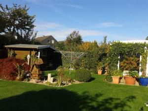 un cortile con un giardino con piante e un capanno di Ferienwohnung Zwergmöwe In Neue Tiefe a Fehmarn