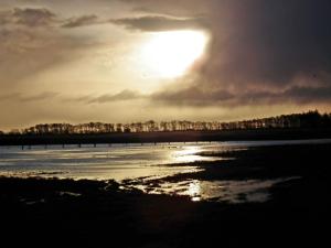 un tramonto su una spiaggia con il sole nel cielo di Ferienwohnung Zwergmöwe In Neue Tiefe a Fehmarn Altre 27 foto