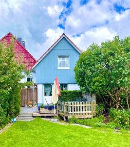 une maison bleue avec une clôture dans la cour dans l'établissement Friesenhuus, à Butjadingen