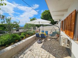 eine Terrasse mit einem Sonnenschirm und Stühlen sowie einem TV in der Unterkunft Spirit of the Sea in Dramalj