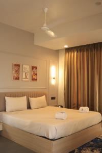 PimpalwandiにあるHotel Siddhesh INNの大きなベッドとタオル2枚のある寝室