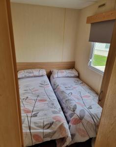 two beds in a small room with a window at Meadow Lakes 39 in Skegness