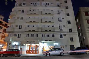 a tall white building with cars parked in front of it at Hotel Dom Rafael Executivo in Santa Maria