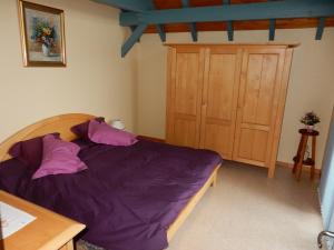a bedroom with a bed with purple sheets and a wooden cabinet at Les hauts du Schliffels in Fellering