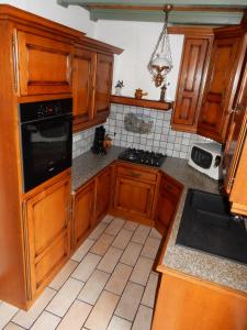 a kitchen with wooden cabinets and a black appliance at Les hauts du Schliffels in Fellering +14 photos
