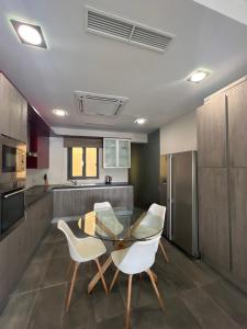 a kitchen with a glass table and white chairs at Front Row Seafront House with Dreamy Valletta and Harbour Sunset Views in Kalkara