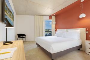 a bedroom with a bed and a desk and a window at Golden Tulip Hotel & Rooftop Martigues Provence in Martigues +24 photos