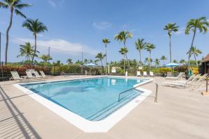 une piscine avec chaises longues et palmiers dans l'établissement Big Island Keauhou Punahele C104 by Coldwell Banker Island Vacations, à Kailua-Kona