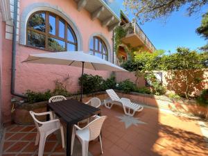 a patio with a table and chairs and an umbrella at Casa Captain Howard Blackburn - fronte mare con giardino - Santa Teresa di Gallura in Santa Teresa Gallura