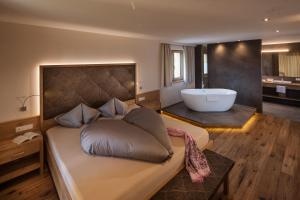a bedroom with a large bed and a bath tub at Romantik Chalet im Weingut Eichenstein in Merano