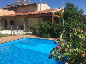 a blue swimming pool in front of a house at Las Lucías, experiencias de ecoturismo in Navatrasierra