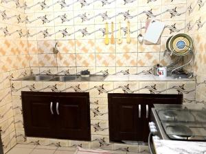 cocina con fregadero y pared de azulejos en Cozy Apartment near the GMK stadium, en Cotonou
