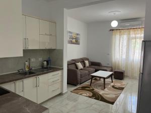 a kitchen and a living room with a couch at Horizont City-Center in Shkodër