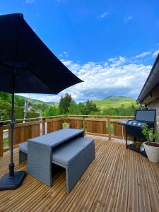 a patio with a table and an umbrella on a deck at Gîtes les cocons des guédons Le Douglas in Le Ménil
