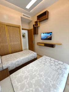 a bedroom with two beds and a tv on the wall at Appart Moderne Vue mer latérale & piscine - Plage des Sablettes El Mansouria in Ben Slimane +26 photos