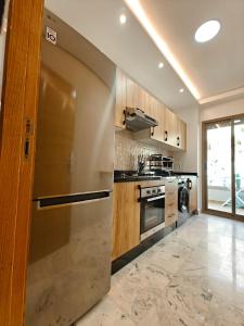 a kitchen with a stainless steel refrigerator and a stove at Appart Moderne Vue mer latérale & piscine - Plage des Sablettes El Mansouria in Ben Slimane