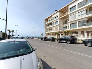 a row of cars parked in front of a building at Appart Moderne Vue mer latérale & piscine - Plage des Sablettes El Mansouria in Ben Slimane