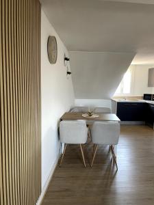 a dining room table with two chairs and a clock on the wall at Au pays des bretzels in Horbourg +3 photos