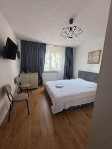 a bedroom with a bed and a chair and a desk at Aurora&Aziz Home in Galaţi
