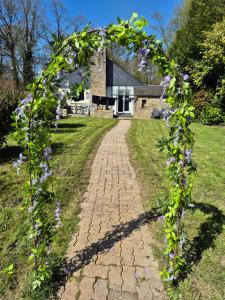 an arch covered in purple flowers on a brick road at Home from home in Le Haut-Corlay