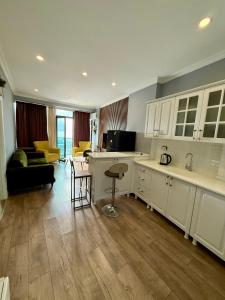 une cuisine avec des armoires blanches et un salon dans l'établissement Metrocity residence d, à Batoumi