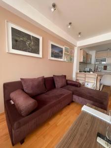 a living room with a brown couch and a kitchen at Velvet Living Luxury Apartment in Skopje +34 photos